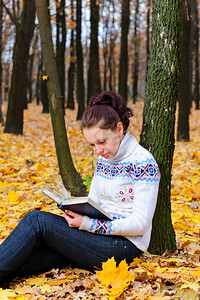 那个有魅力的女人在秋天森林里读了那本书背景图片