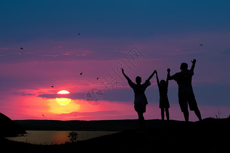 举起孩子三个人的家庭欢迎日落太阳背景
