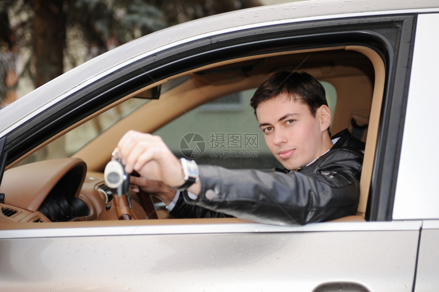 年轻快乐的男子肖像展示钥匙坐在新车里图片