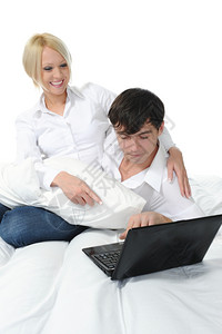 床上躺着笔记本电脑的年轻夫妇图片