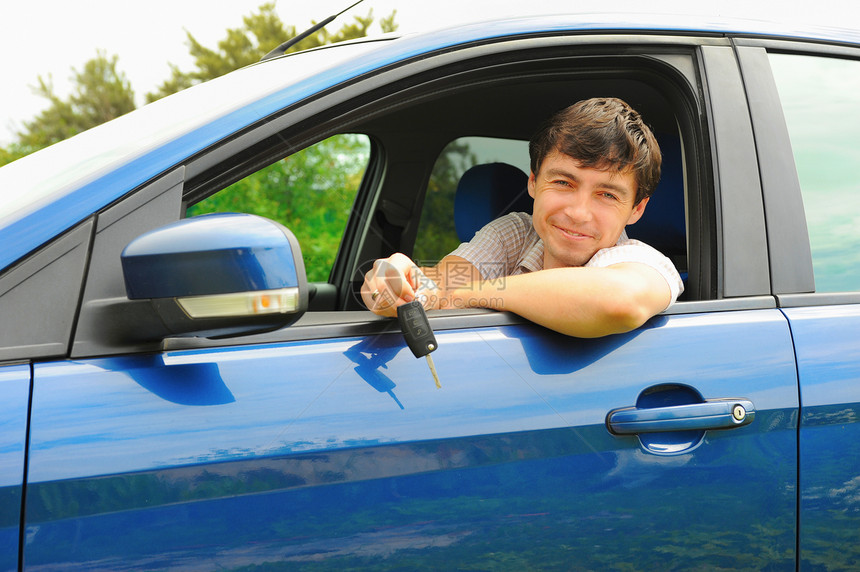 年轻快乐的男子肖像展示钥匙坐在新车里图片