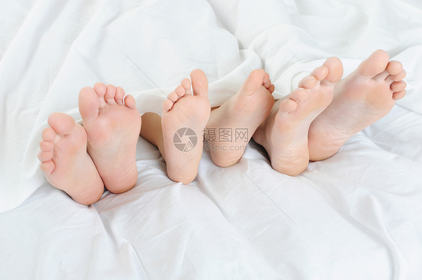 床上一户人家的脚贴紧孤立在白色背景上图片