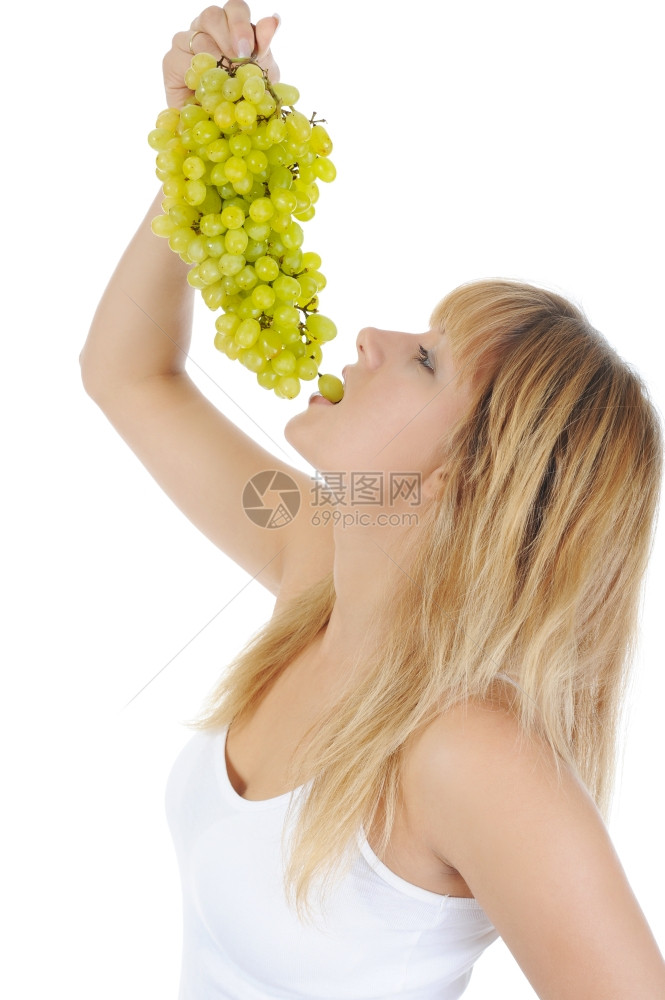 年轻金发女孩吃葡萄孤立于白种背景图片