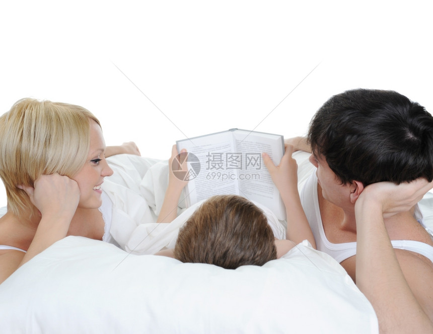 男孩子读书给在床上的父母看书孤立于白人背景图片