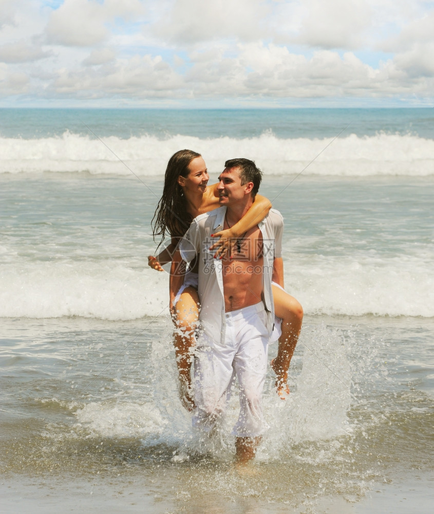 在阳光明媚的海滩上相爱年轻美夫妻图片