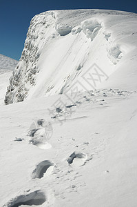 寒冬陡峭的悬崖壁和雪上人类足迹接连到悬崖边乌克兰喀尔巴阡山斯维多茨海脊布雷兹尼察山背景图片