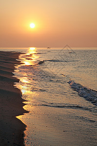 阳光照的沙岸和渔船远处的光影高清图片