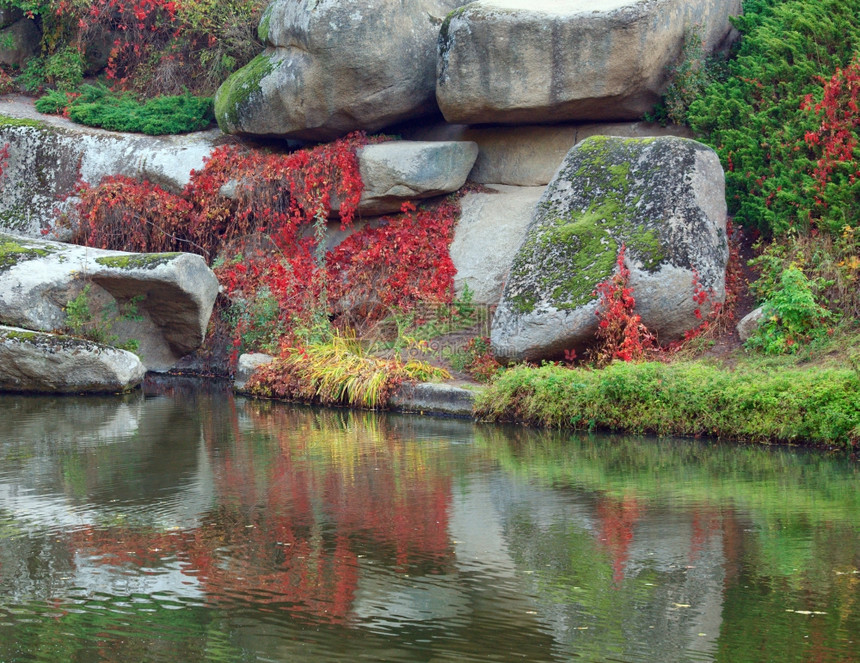 秋季公园中大石头反射而成的池塘水面图片