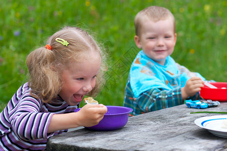两个小孩在户外餐桌上吃饭图片