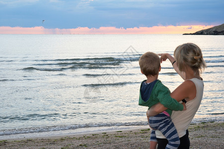 夜间海边岸和母亲带小男孩没有重点图片