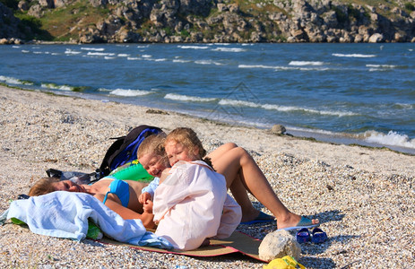 快乐的家庭有小孩母亲在沙滩上放松图片