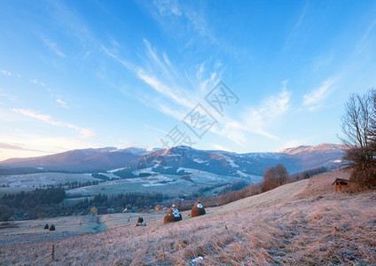 第一个秋天草地上霜和干堆山村日出图片