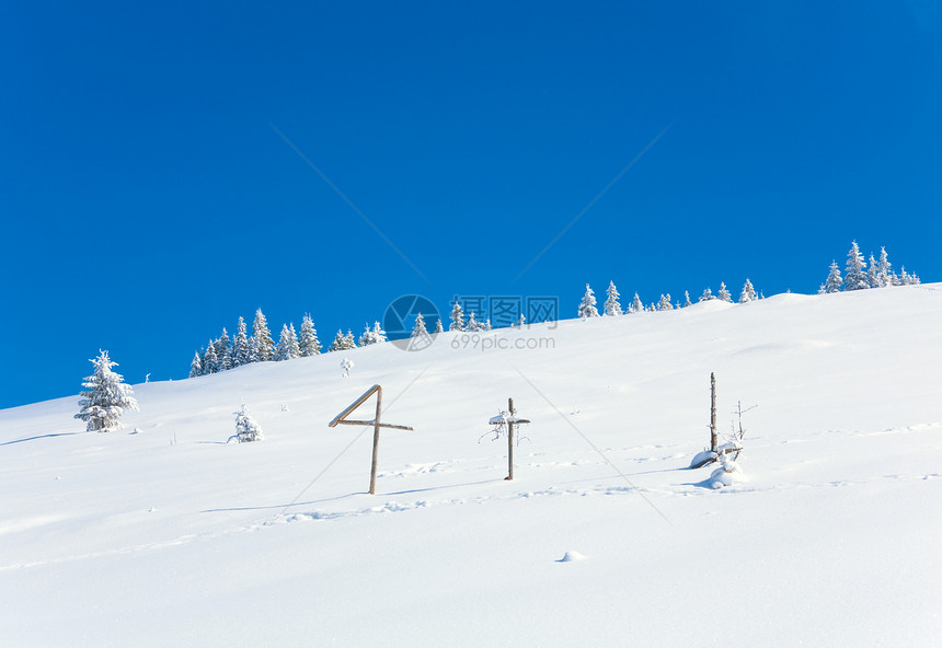 山边蓝天空背景和前面木十字的山坡上冬季雪壁树喀尔巴阡山乌克兰图片