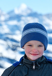 冬天山地背景的快乐男孩肖像图片