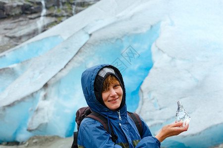 在尼加德斯布雷恩冰川背景上手握一块冰的光辉快乐妇女挪威图片