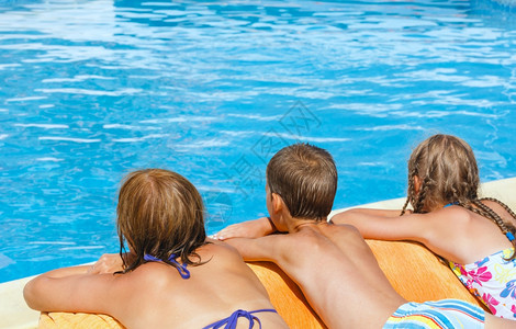 母亲和孩子一起在游泳池附近的阳光下晒太图片