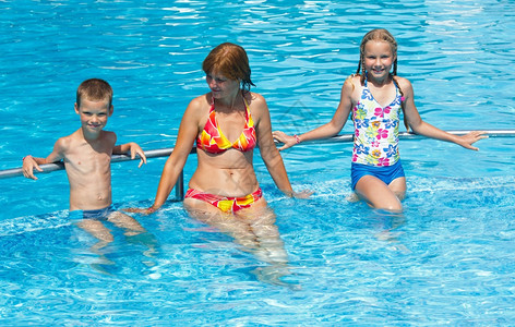 母亲和她的孩子在夏季户外游泳池里图片