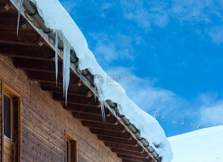 冬季山坡上的木屋顶有雪和冰块图片