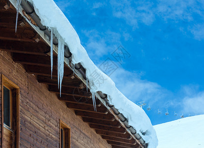 冬季山坡上的木屋顶有雪和冰块图片