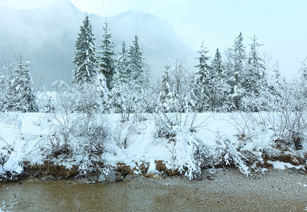 冬天的小溪流河岸上有雪树雾中山上也有雪树图片