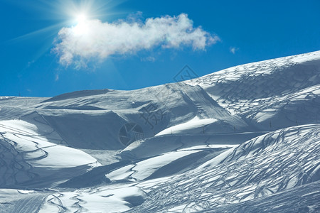 希尔赛德在蓝色的天空里带着阳光和孤独的乌云摇欲坠的滑雪足迹图片