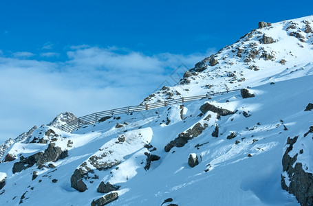 上午冬季阿尔卑斯山景岩石坡上有木栅栏奥地利提洛尔图片