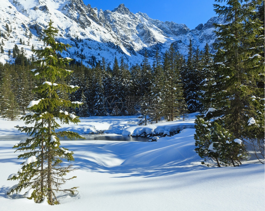 小山流和冬季雪地岩坡上的森林图片