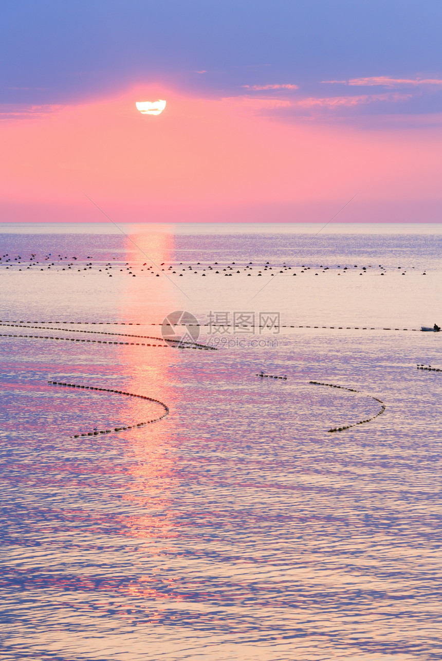 美丽的迷人清晨海景与日出太阳轨道在地表和渔网上图片