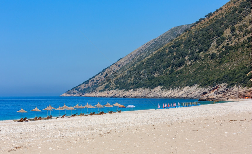 夏季上午海滩有水防晒床和草墨遮阳阿尔巴尼亚图片