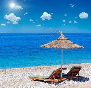 夏晨阳光明媚的沙滩有日晒和草润的遮阳阿尔巴尼亚深蓝天空有相同的积聚云两针缝合高分辨率图像背景图片