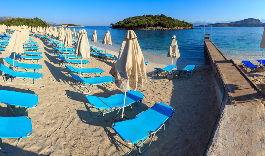 夏季早晨沙滩子Ksamil海滩带防晒床和罩阿尔巴尼亚两针缝合全景图片