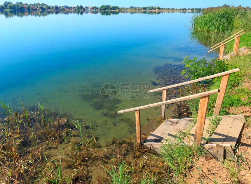 夏季湖平原海滩与木制楼梯通向水面平静的乡村生活态友好旅游露营捕鱼的概念图片
