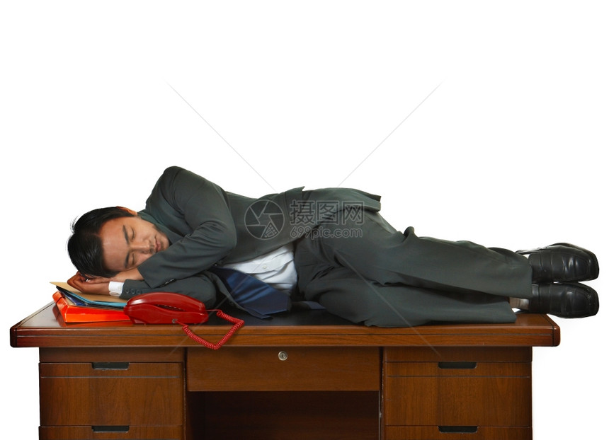 在他的办公室桌前睡觉的疲劳商人图片