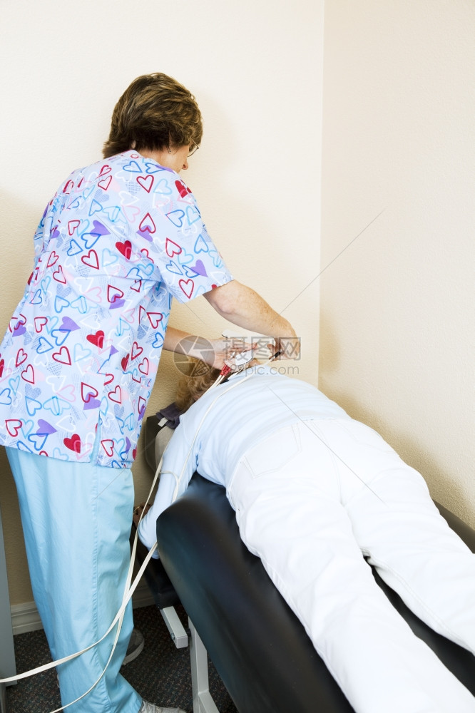 卫生局的物理治疗师在病人背部施以电刺激图片