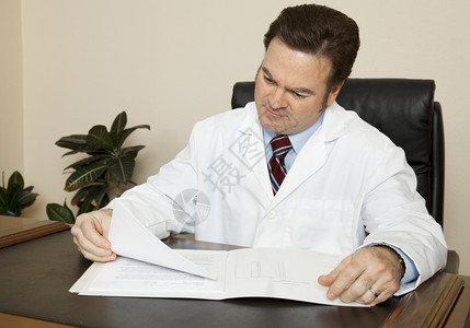 书桌旁的英俊医生翻阅病人历表图片