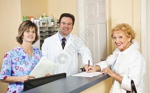 医生及其护士接待员在病人签名时向问好并提供医疗保险信息图片