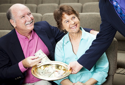 一对夫妇把钱放在教堂的收藏盘里图片