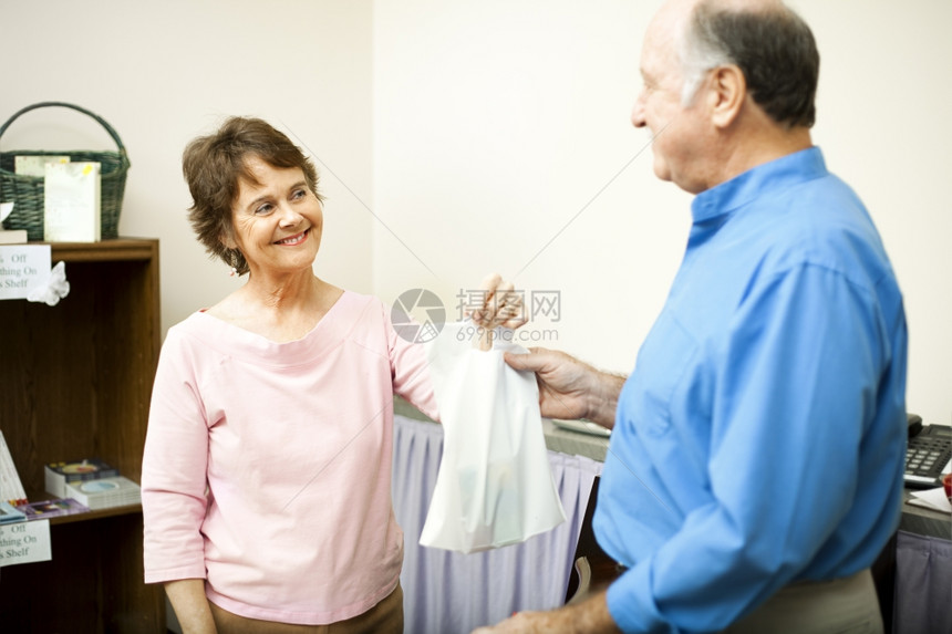 友好的商店办事员带着微笑把一个顾客的包交给他顾客图片
