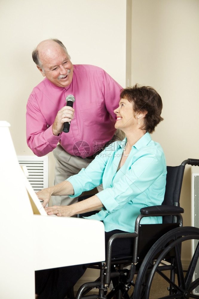 坐在轮椅上的音乐家在她丈夫唱歌时弹钢琴图片