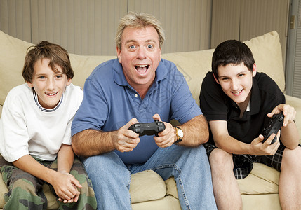 叔或父亲和两个男孩玩电子游戏图片