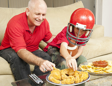 父亲和儿子一起看足球吃零食图片