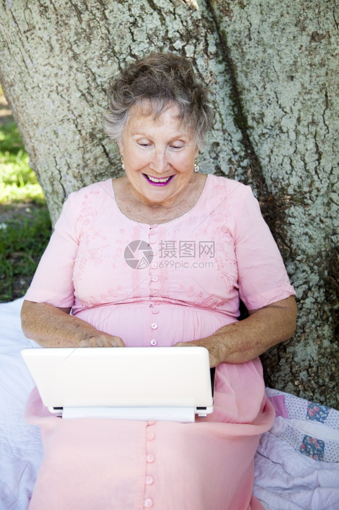 年长妇女喜欢在户外使用网本电脑图片