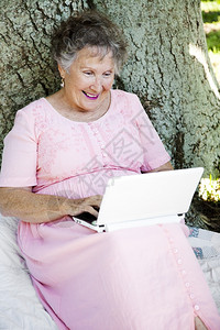 坐在户外的老年妇女在网上电脑读她的子邮件图片