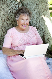 高级女在树下户外使用她的新网本电脑背景图片
