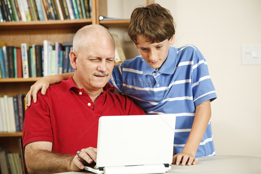 帮助中年父亲使用电脑的小男孩图片
