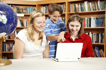 两个小女孩和一男在学校图书馆里使用网电脑图片