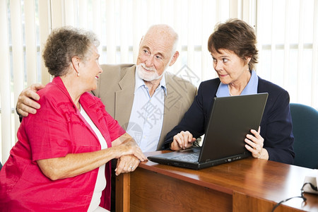 老年夫妇和他们的财务顾问在电脑上翻他们的退休收入图片