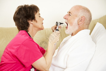 家庭保健护士用和舌头压抑剂检查病人的口腔图片