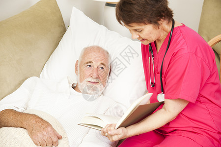 友善的家庭护理者向一位年长的病人朗读图片
