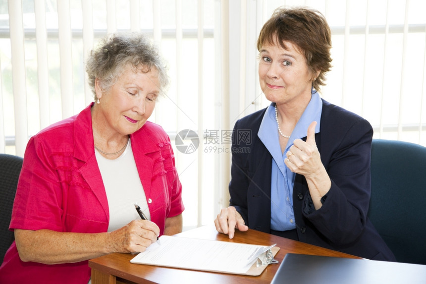 成熟的女商人在她高级客户签署销售协议时给人一个拇指图片